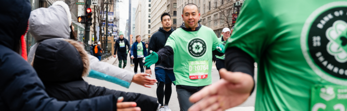 Participants high fiving spectators during the 2025 Bank of America Shamrock Shuffle