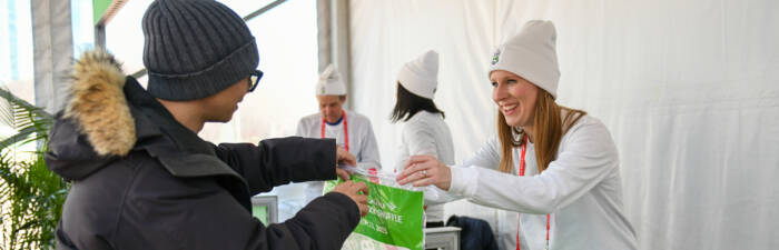 Volunteer handing a participant packet to a participant at the 2025 Bank of America Shamrock Shuffle